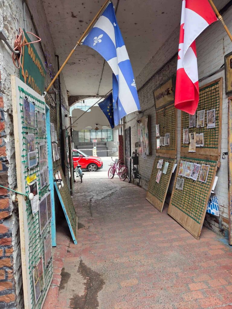 Alleyway leading from the street into an art store lined with artwork created by the local artists
