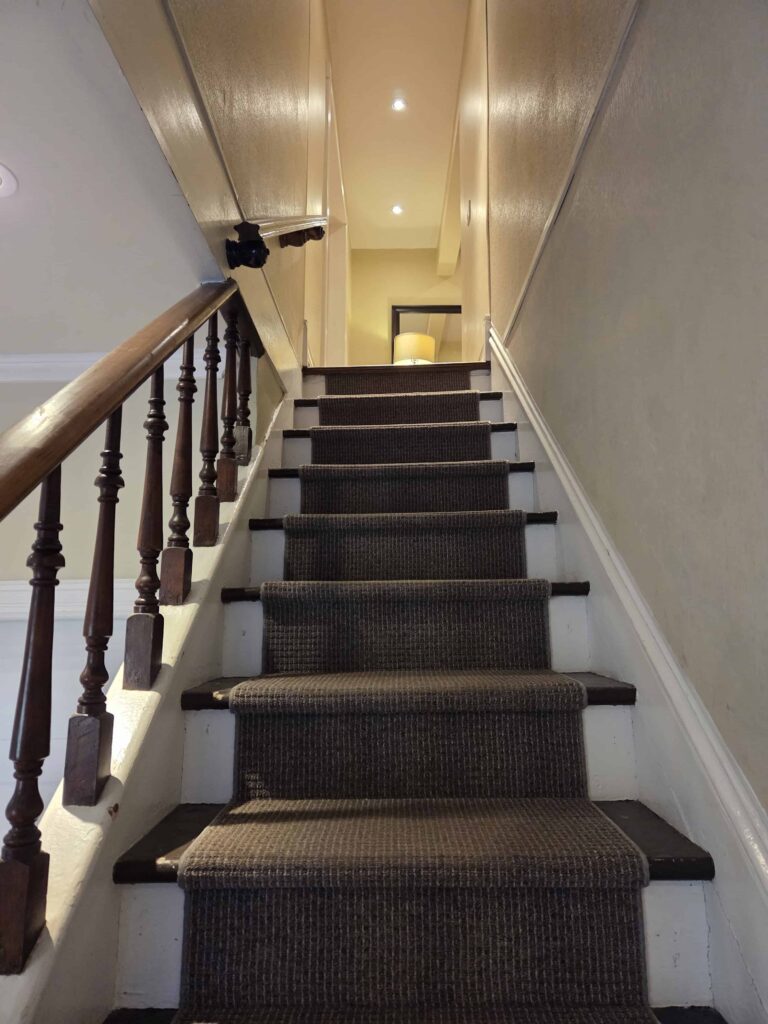 A long flight of stairs leading to 2 upstairs suites from the lobby of the Newsroom Suites in Wellington Ontario